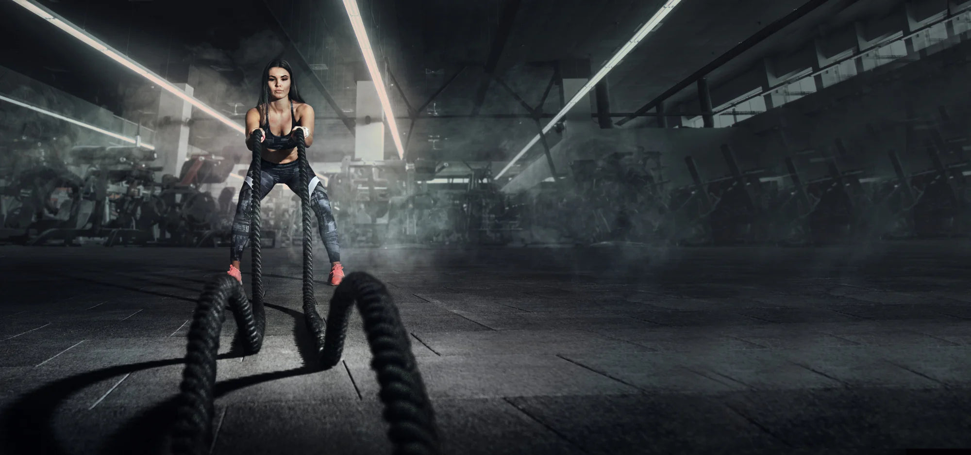 Woman exercising with ropes in a dark warehouse setting